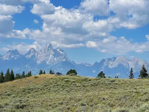 Grand Tetons beyond a grassy hill with tent