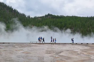 People standing and walking above hot spring steam