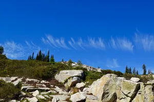 Short, wispy clouds above a rocky trail