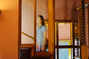 Woman blurring up the stairs amidst wooden Gaudi architecture