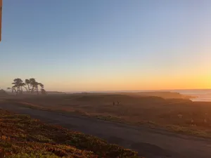 Dramatic ocean sunset with hazy tropical trees in the distance