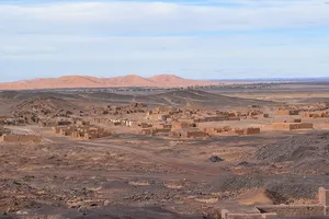 Vista of sandstone structures with dunes in the distance