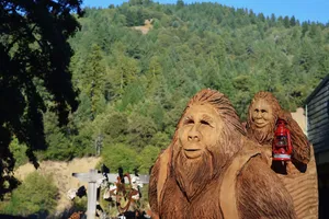 Wooden statue of bigfoots with forest background