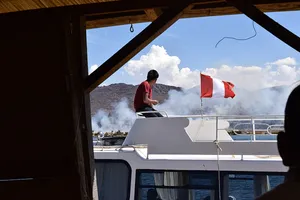 Young man on top of boat with flag of Peru