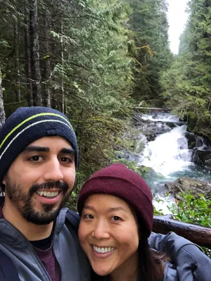 Couple in beanies in front of a forest creek