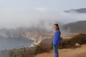 Woman above ocean with Bixby canyon bridge in the background