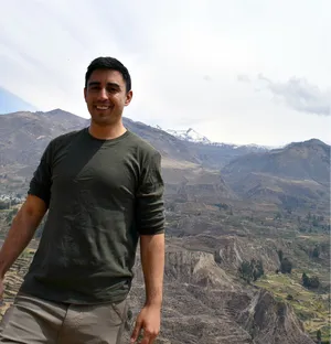 Andrew in front of terraced farmland and snowy peaks