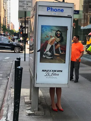 Legs in red heels poking out beneath a phone booth